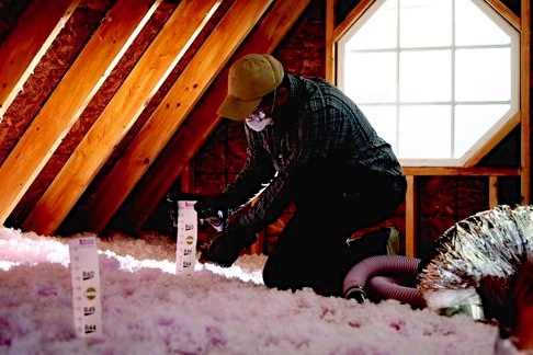 a technician installs attic insulation